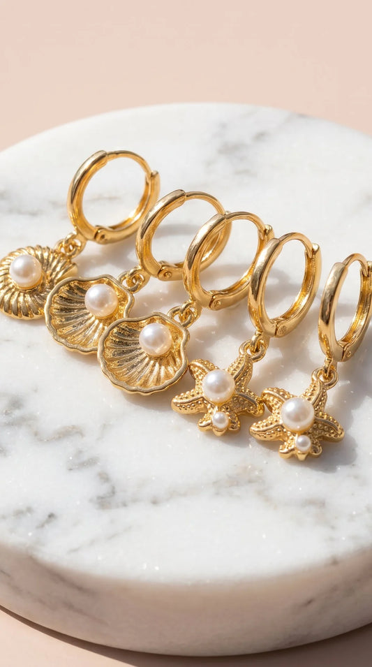 Set of gold hoop earrings with pearls on a marble surface