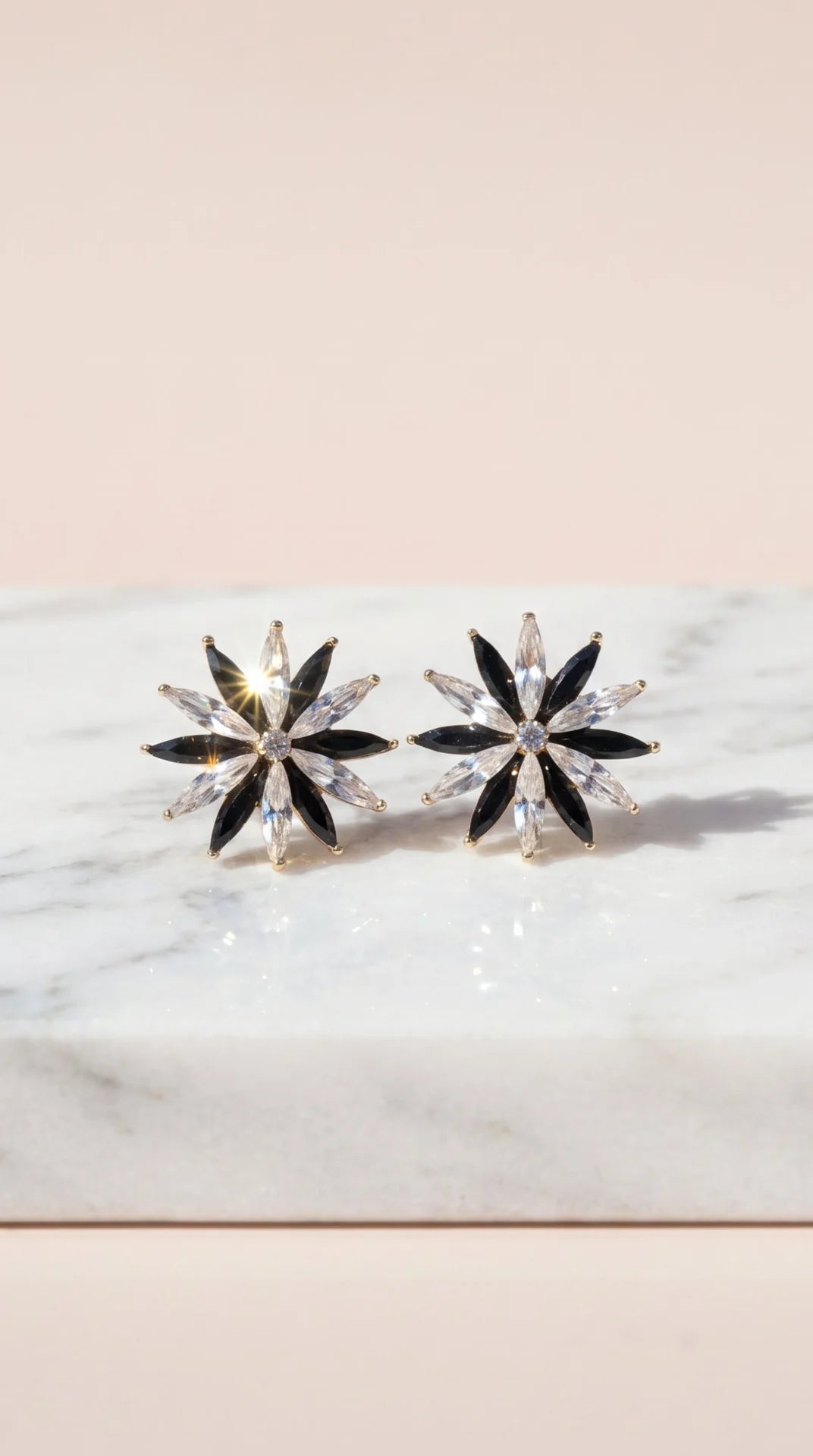 Pair of star-shaped earrings on a marble surface with a light pink background